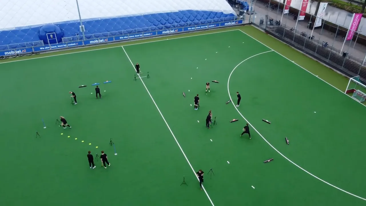 Dronebeeld van een teamtraining met Beams op een hockeyveld