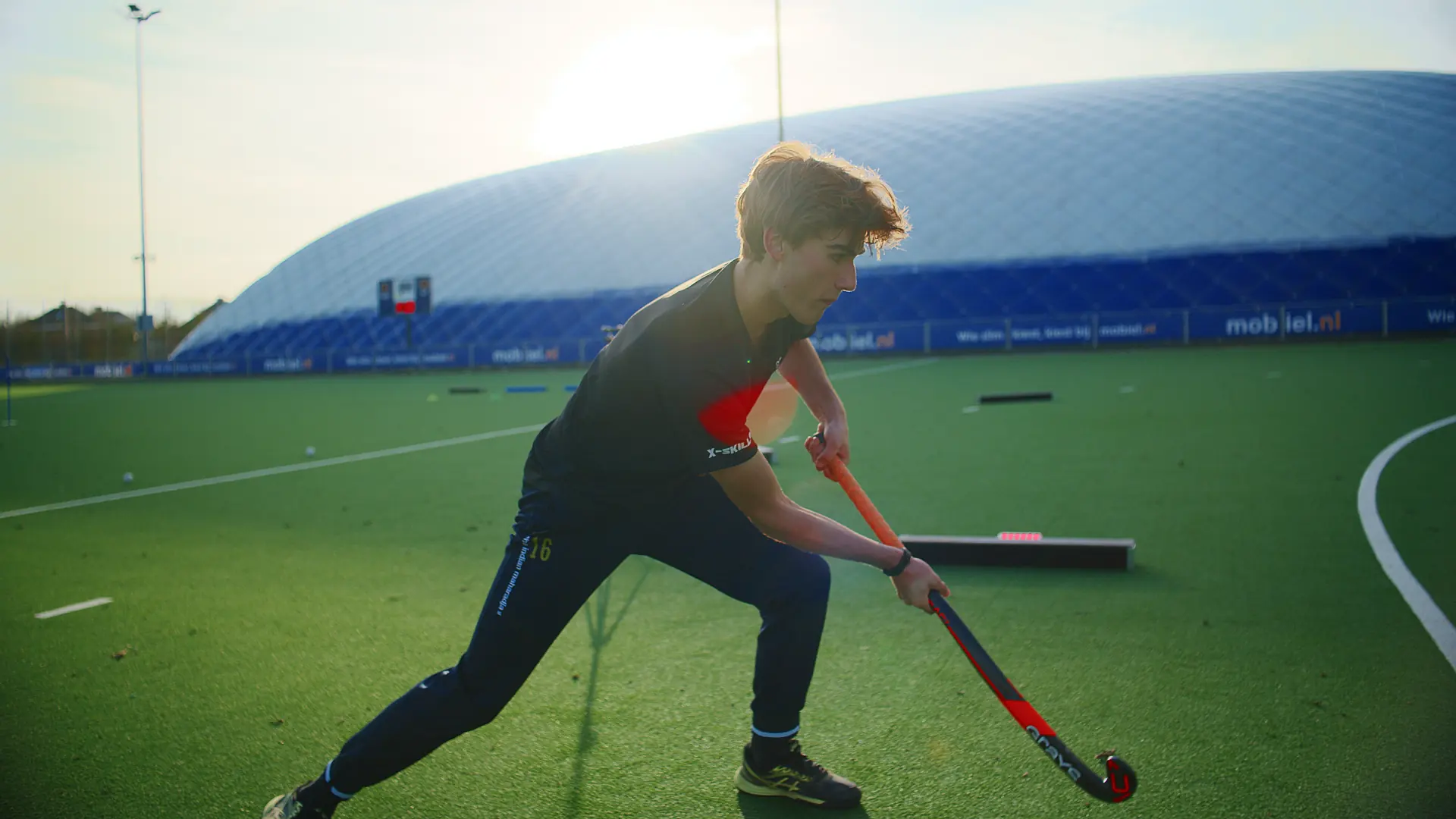Hockeyspeler slaat aan bij de Beams in het avondlicht